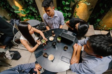 Grup Asya iş bir masa etrafında oturup çalışmaları hakkında sohbet vardır. Onlar konuşurken onlar gülümseyen ve rahat.