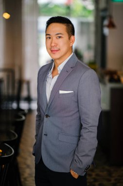 Bir genç, profesyonel ve yakışıklı Çinli Asyalı avukat portresi. O gri renk takımlı ve beyaz cep kare ve kameraya gülümseyen. O iyi bakımlı ve birlikte koymak ve gülümsüyor.