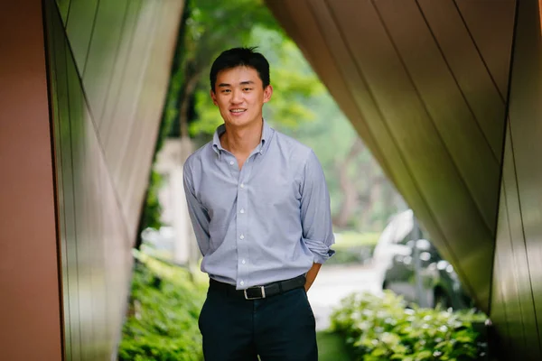 近未来的な構造のロビーに立っている若い 中国アジア系のビジネスマンの肖像画 彼は背の高い ハンサムな手入れ 自信を持って彼は立っているし カメラに微笑みかける — ストック写真