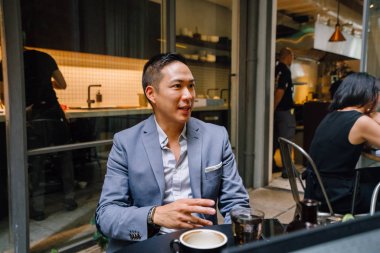 bir masa etrafında oturan genç ve enerjik Çin Asya alt grup ve ışık yürekli iş tartıştık. Gülümseyen ve onlar konuşmak ve sohbet gibi gülüyor.