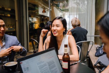 Grup Asya iş bir masa etrafında oturup çalışmaları hakkında sohbet vardır. Onlar konuşurken onlar gülümseyen ve rahat.