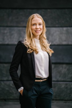 Bir beyaz, portre profesyonel bir takım bir koyu gri arka plan beyaz ve çekici orta yaşlı bir kadın. Sarı saçları ve mavi gözleri ve gülümseyen güzel bir kız 