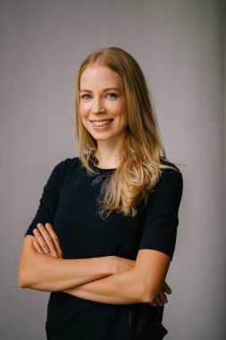 Beyaz bir arka plan karşı bir profesyonel, çekici ve sarışın Rus kadın portresi. O bir expat Asya ve siyah bir elbise giyiyor ve güven projeler iken gülümsüyor.