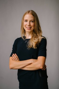 Beyaz bir arka plan karşı bir profesyonel, çekici ve sarışın Rus kadın portresi. O bir expat Asya ve siyah bir elbise giyiyor ve güven projeler iken gülümsüyor.