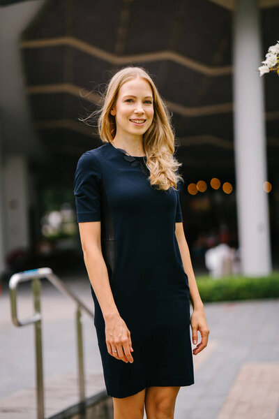 Portrait of a very beautiful white Caucasian woman in a black dress. She is blond with blue eyes, middle-aged, attractive, beautiful and smiling. She is a Russian expatriate living in Singapore.