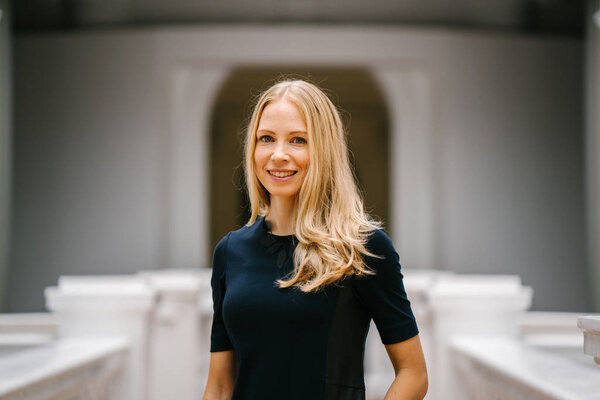 professional head shot / close up of a young Russian businesswoman. She is in startup and is dynamic, energetic and confident as she smiles at the camera and has blue eyes and blond hair.
