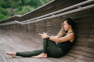 Bir köprü bir parkta gür, yeşil genel Singapur sportif, aktif giyim gün hafta sonu boyunca çekici, genç Çinli Asyalı bir kadın portresi giymiş.