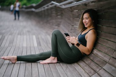 Sportif, aktif giyim telefon ile çekici, genç Çinli Asyalı bir kadın portresi giymiş. 