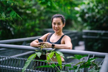 Sportif, aktif giyim telefon ile çekici, genç Çinli Asyalı bir kadın portresi giymiş. 