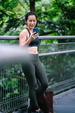 Sportif, aktif giyim telefon ile çekici, genç Çinli Asyalı bir kadın portresi giymiş. 