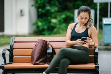 Sportif, aktif giyim telefon ile çekici, genç Çinli Asyalı bir kadın portresi giymiş. 