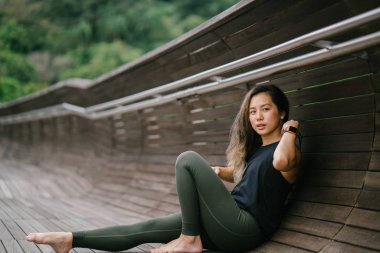 Bir köprü bir parkta gür, yeşil genel Singapur sportif, aktif giyim gün hafta sonu boyunca çekici, genç Çinli Asyalı bir kadın portresi giymiş.