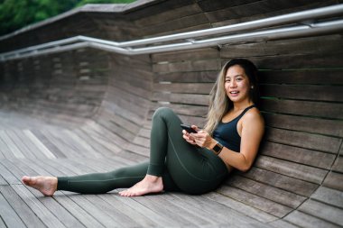 Sportif, aktif giyim telefon ile çekici, genç Çinli Asyalı bir kadın portresi giymiş. 