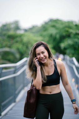 Sportif, aktif giyim telefon ile çekici, genç Çinli Asyalı bir kadın portresi giymiş. 