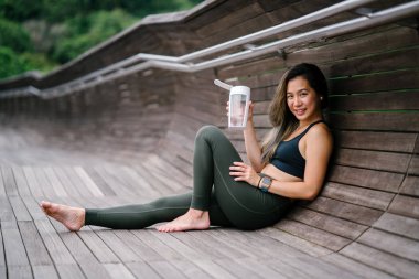 Çekici, genç Çinli Asyalı bir kadın portresi sportif, aktif giyim su ile yeşil Parkı Singapur hafta sonu gün içinde giyinmiş.