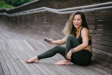 Sportif, aktif giyim telefon ile çekici, genç Çinli Asyalı bir kadın portresi giymiş. 