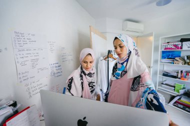 İki genç ve iş stratejisi toplantısı dynamicare işlerini görüşmek üzere. Onlar Müslüman Moda online ve mağaza içi perakende satmak. Ofiste bilgisayar üzerinde çalışan güzel Müslüman kadınlar