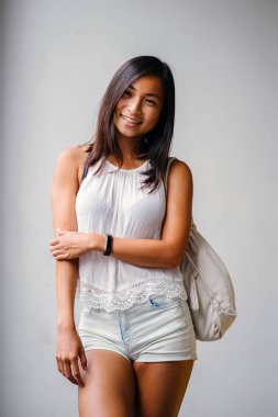 Stüdyo bir şirin, atletik ve tabaklanmış Çinli Asyalı kadın portresi. O beyaz bir arka plan karşı duruyor ve konforlu için sıcak hava rahat kıyafetler giymiş gibi gülümsüyor.