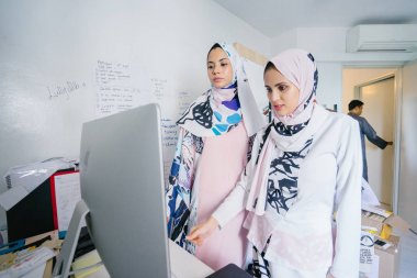 İki genç ve iş stratejisi toplantısı dynamicare işlerini görüşmek üzere. Onlar Müslüman Moda online ve mağaza içi perakende satmak. Ofiste bilgisayar üzerinde çalışan güzel Müslüman kadınlar
