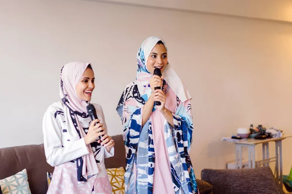 Duas Mulheres Muçulmanas Lenços Cabeça Estão Cantando Karaoke Seu Sistema — Fotografia de Stock