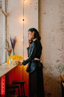 Portre bir şık, şık ve ince Malay Müslüman kadının bir kafe veya alan gün boyunca coworking. O bir fan tutuyor 