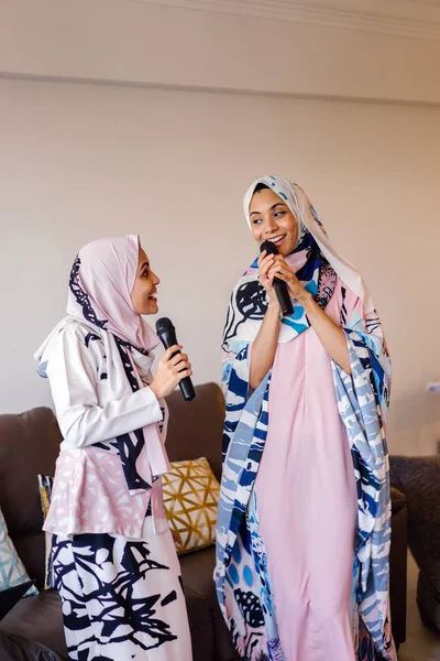 Duas Mulheres Muçulmanas Lenços Cabeça Estão Cantando Karaoke Seu Sistema — Fotografia de Stock