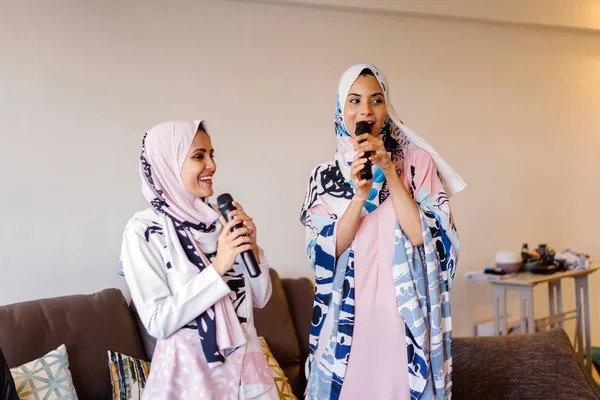 Duas Mulheres Muçulmanas Lenços Cabeça Estão Cantando Karaoke Seu Sistema — Fotografia de Stock