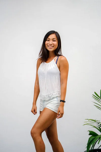 Portrait of a candid moment for an young, athletic and tanned Chinese Asian woman. She is smiling and is dress casually and comfortably.