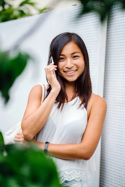 Hareket eden telefon ile gün içinde gülümseyen atletik, tonda ve tabaklanmış Çinli Asyalı kız. 