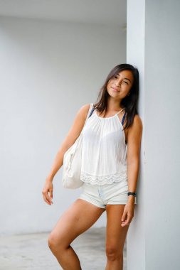 Stüdyo bir şirin, atletik ve tabaklanmış Çinli Asyalı kadın portresi. O beyaz bir arka plan karşı duruyor ve konforlu için sıcak hava rahat kıyafetler giymiş gibi gülümsüyor.