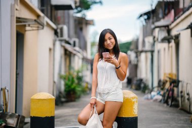 Gün boyunca Asya'da bir sokakta onun smartphone kullanarak bir genç, atletik, çekici ve şirin Çinli Asyalı kız portresi. O tabaklanmış, minyon ve rahat..