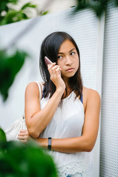 Athletic, toned and tanned Chinese Asian girl smiling with mobile phone in the day.