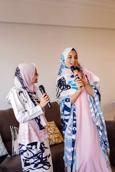 Duas Mulheres Muçulmanas Lenços Cabeça Estão Cantando Karaoke Seu Sistema — Fotografia de Stock