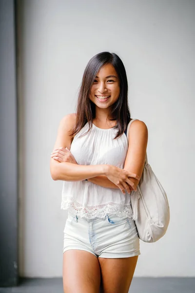 一个可爱的 运动的 晒黑的亚洲华人女孩的肖像 在街上走着灰色的背景 — 图库照片