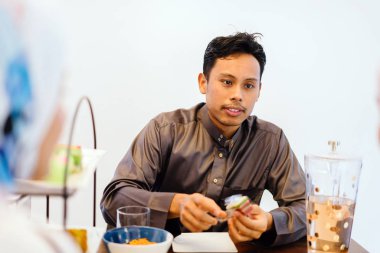 Hari Raya Festival döneminde evde lezzetli bir yemek keyfi Müslüman orta yaşlı bir erkek portresi.