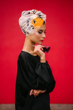 Orta Doğu kökenli güzel, uzun boylu ve şık bir kadın moda portre. O kırmızı, düz arka planı poz.
