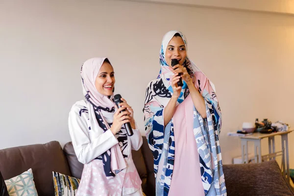 Duas Mulheres Muçulmanas Lenços Cabeça Estão Cantando Karaoke Seu Sistema — Fotografia de Stock