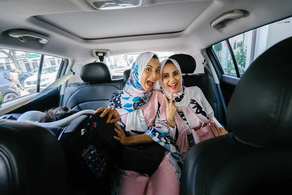 Two Muslim women in headscarves in car