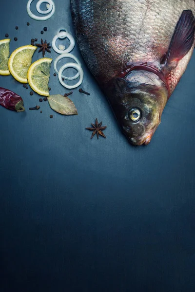 Lezzetli taze balık ve aromatik otlar, baharatlar ve sebzeler karanlık kayrak plaka üzerinde istiridye