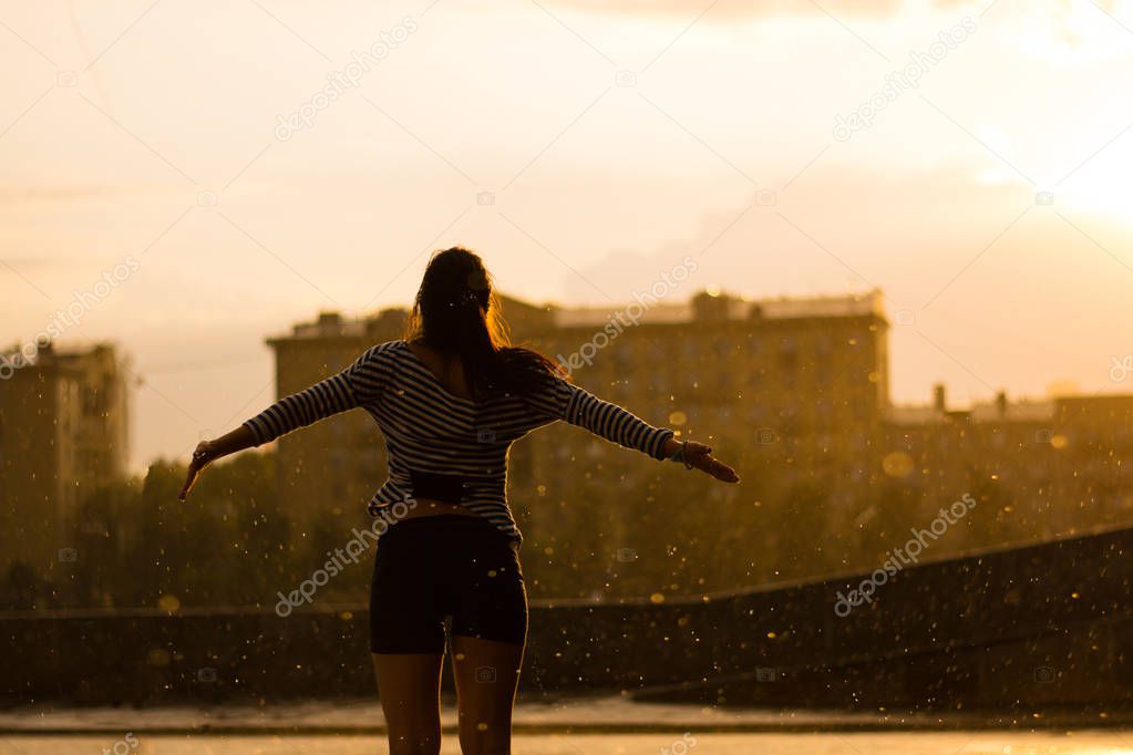 Woman stand under the rain on sunset background