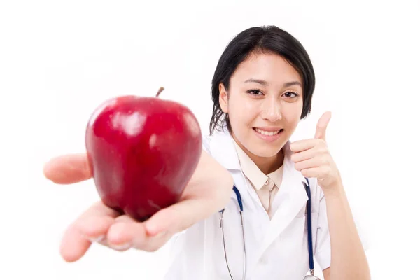 Sonriente doctora sugiriendo manzana roja, dando el pulgar hacia arriba gest — Foto de Stock