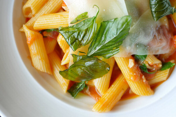 basil and cheese on top of penne pasta