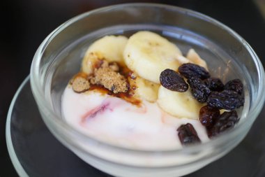 dilimlenmiş muz ve kuru üzüm ile yoğurt