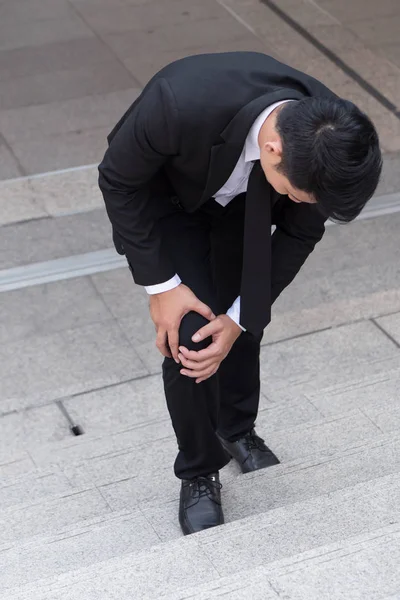 Hombre de negocios con dolor de rodilla, concepto de obstáculo — Foto de Stock
