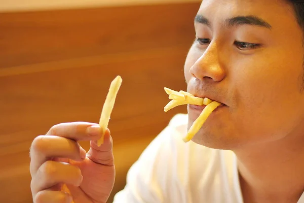 Uomo mangiare patatine fritte, patate fritte, patatine fritte, spazzatura malsana veloce — Foto Stock