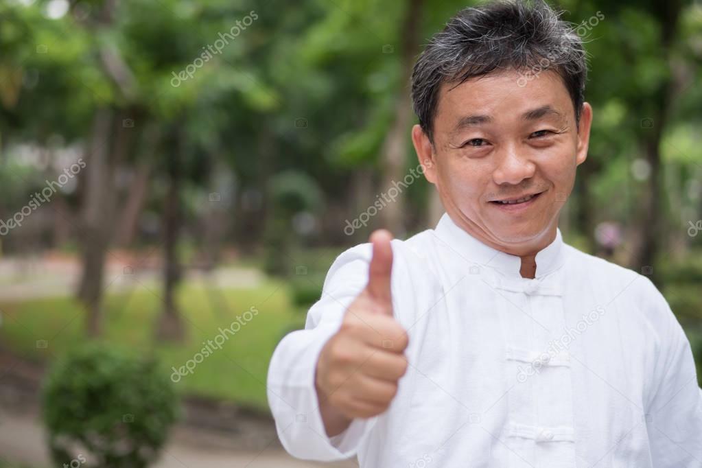asian kung fu senior man showing thumb up hand gesture