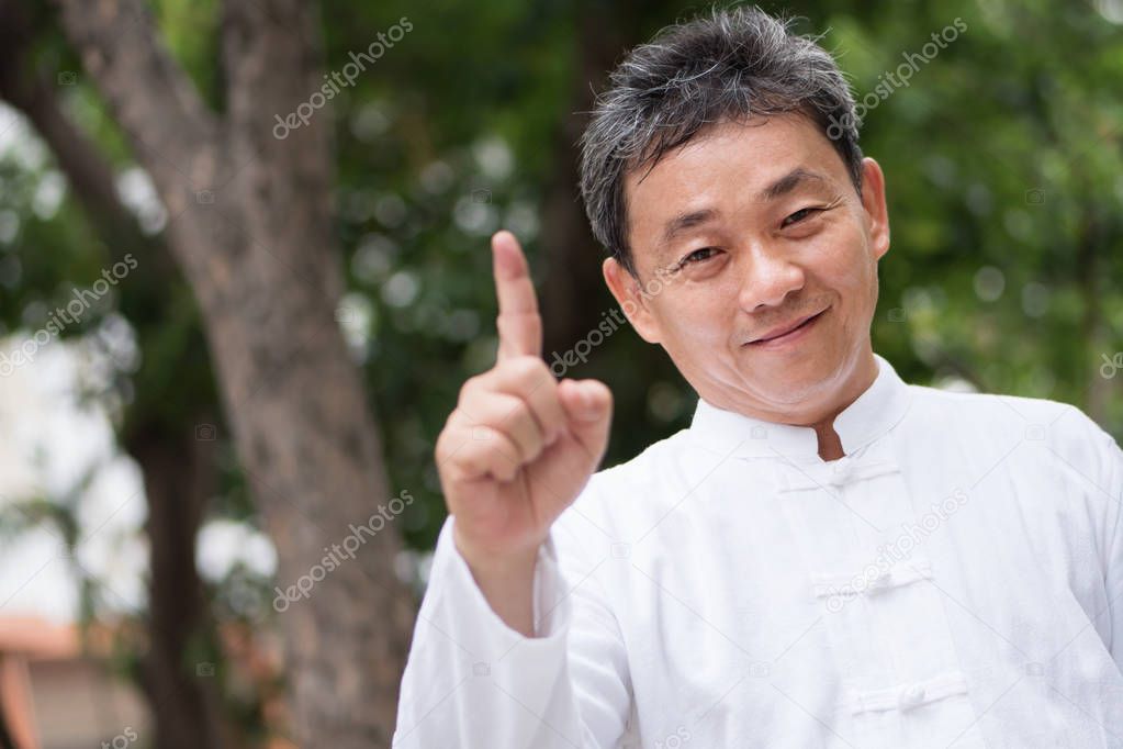 asian kung fu senior man showing number 1 hand gesture
