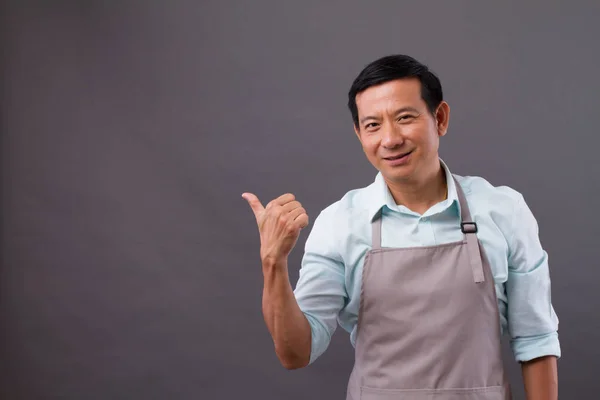 Confident man shopkeeper pointing thumb up to space — Stock Photo, Image