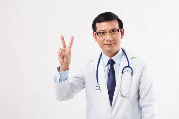 Jistý asijský lékař směřující nahoru 2 prsty, Vítězné gesto — Stock fotografie