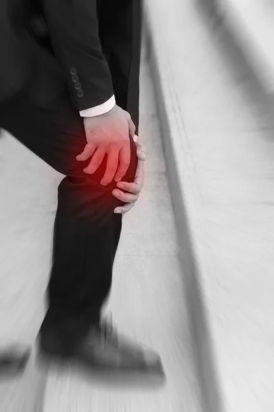 Hombre de negocios con dolor de rodilla, concepto de obstáculo — Foto de Stock